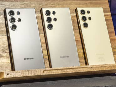 Trois Samsung Galaxy S24 Ultra alignés sur un pupitre en bois et vus de dos