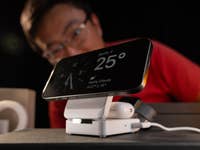 Un iPhone vu de face et posé sur un chargeur à induction.