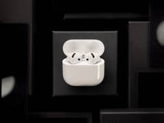 AirPods blancs d'Apple dans leur étui de chargement sur un fond sombre.