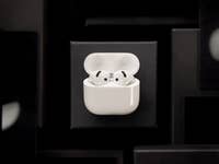 AirPods blancs d'Apple dans leur étui de chargement sur un fond sombre.