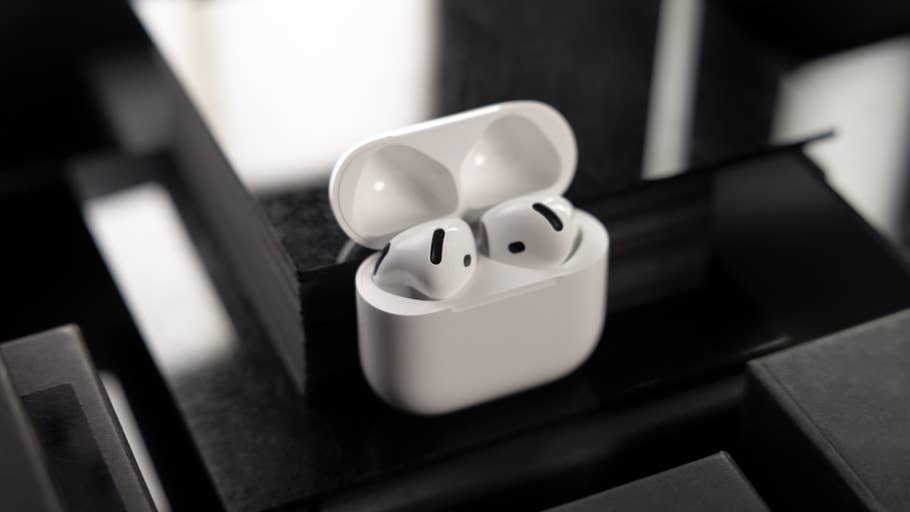 Une paire du0027AirPods du0027Apple dans leur boîtier de chargement, posée sur une surface sombre.