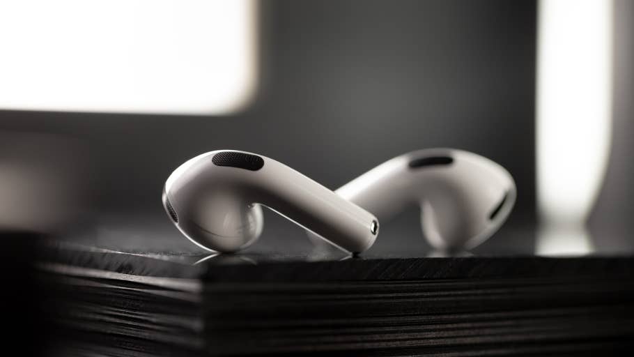Gros plan sur des AirPods Apple reposant sur une surface noire, mettant en valeur leur design épuré.