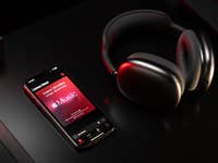 Le casque sans fil Apple AirPods Max posé à coté d'un iPhone avec Apple Music ouvert