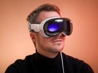 Une personne portant un casque de réalité augmentée Apple Vision Pro sur un fond chaleureux.