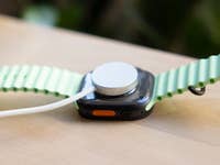 Gros plan d'une Apple Watch Ultra 3 avec un bracelet vert, montrant le dos et le port de charge.