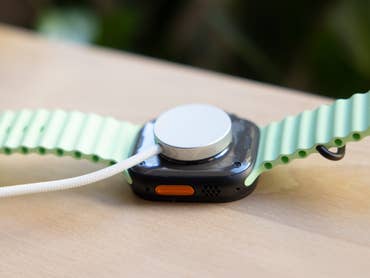 Gros plan d'une Apple Watch Ultra 3 avec un bracelet vert, montrant le dos et le port de charge.