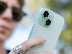 L'iPhone 15 vu de dos avec un zoom sur son double module photo, tenu dans la main par Camilla