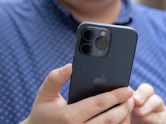 L'iPhone 15 Pro Max d'Apple tenu dans une main droite, vu de dos avec un zoom sur son module photo arrière