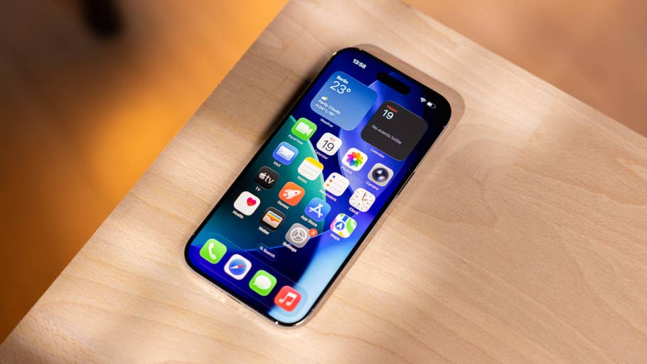 Un iPhone avec une interface d'application colorée sur une surface en bois affichant des widgets météo et calendrier.