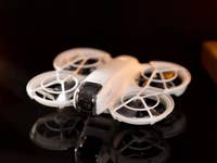 Un drone DJI Neo est affiché sur une surface réfléchissante avec un éclairage doux.