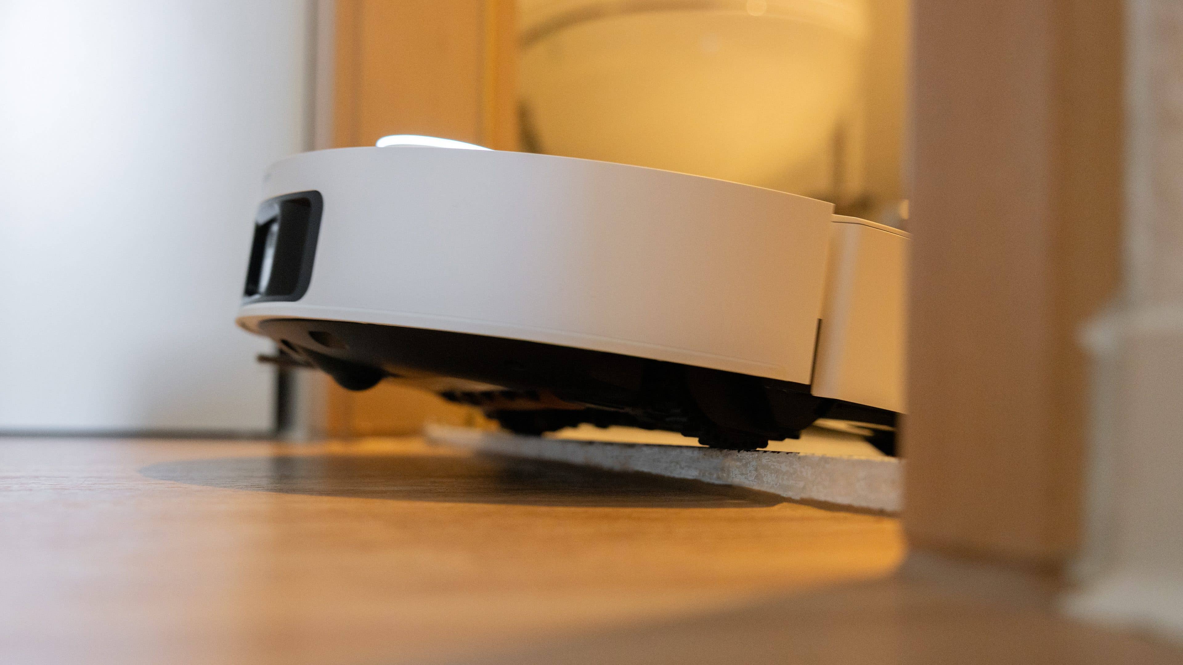 Une vue en contre-plongée du robot aspirateur Dreame X50 Ultra se déplaçant sur un sol en bois.