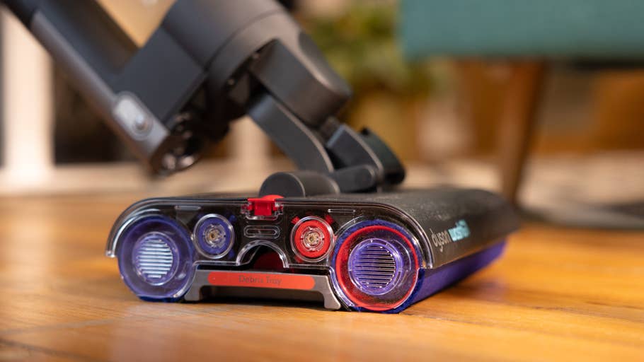 Gros plan du bac à débris du0027un aspirateur Dyson avec des indicateurs colorés sur un sol en bois.