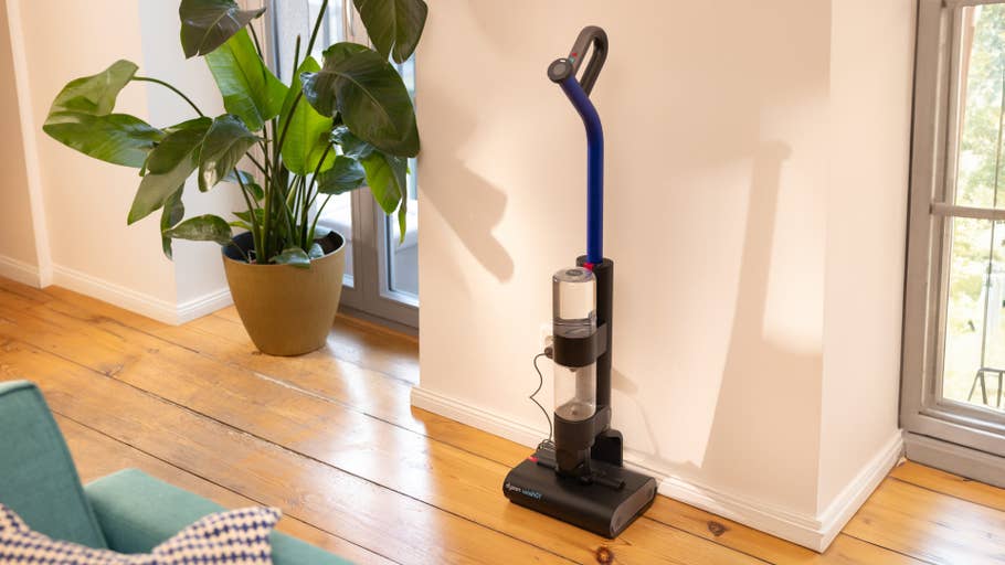 Un aspirateur Dyson Wash G1 est adossé à un mur à côté du0027une grande plante en pot dans une pièce lumineuse.