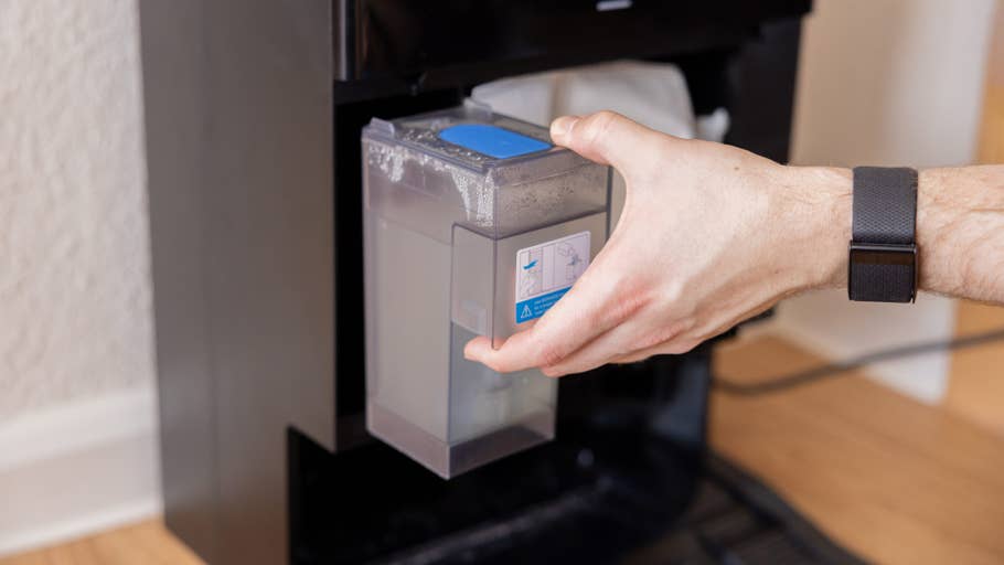 Une personne retire un réservoir du0027eau du0027un appareil noir, probablement lu0027Ecovacs Deebot X8 Pro Omni.