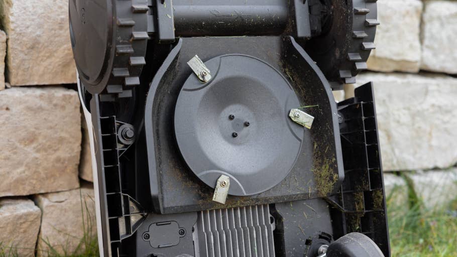 Gros plan du dessous du0027une tondeuse à gazon robotisée avec des lames et des résidus du0027herbe.