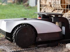 Une tondeuse robotique placée à côté d'une pile de bois.