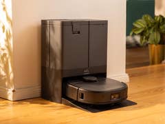 Un aspirateur robot Eufy X10 Pro Omni am doc à côté d'une plante dans une pièce ensoleillée.