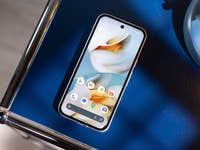 Un smartphone Google Pixel 9a affiché sur une surface bleue à côté d'une lampe bleue.