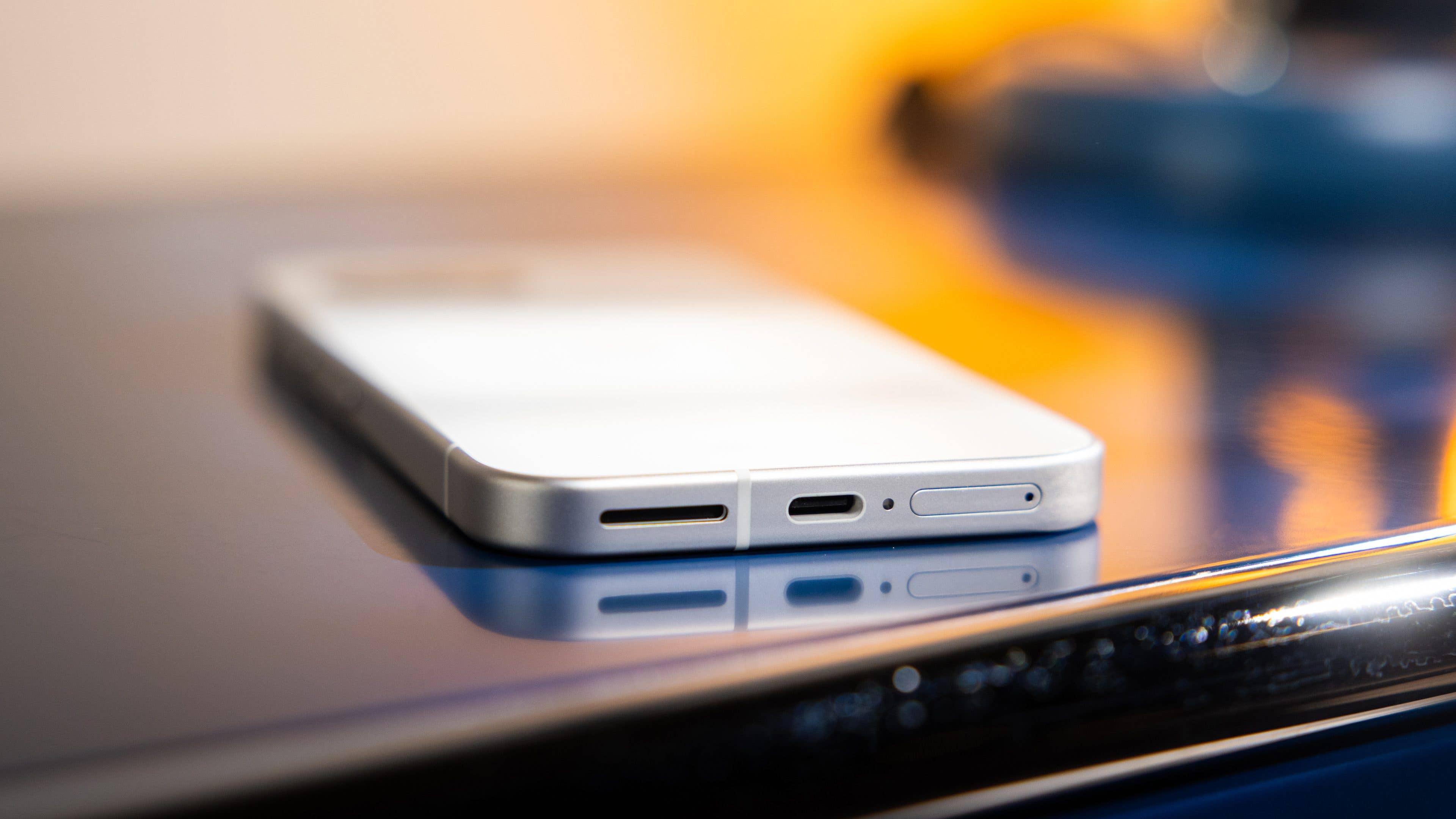 Gros plan sur les ports d'un smartphone Google Pixel 9a sur une surface réfléchissante.