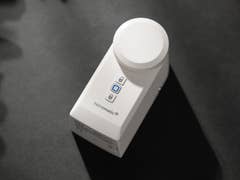 Une serrure intelligente Homematic IP blanche avec un dessus circulaire et deux boutons sur le côté.