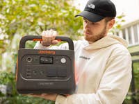 Une personne tenant une station d'alimentation portative Jackery Explorer 1000 à l'extérieur.