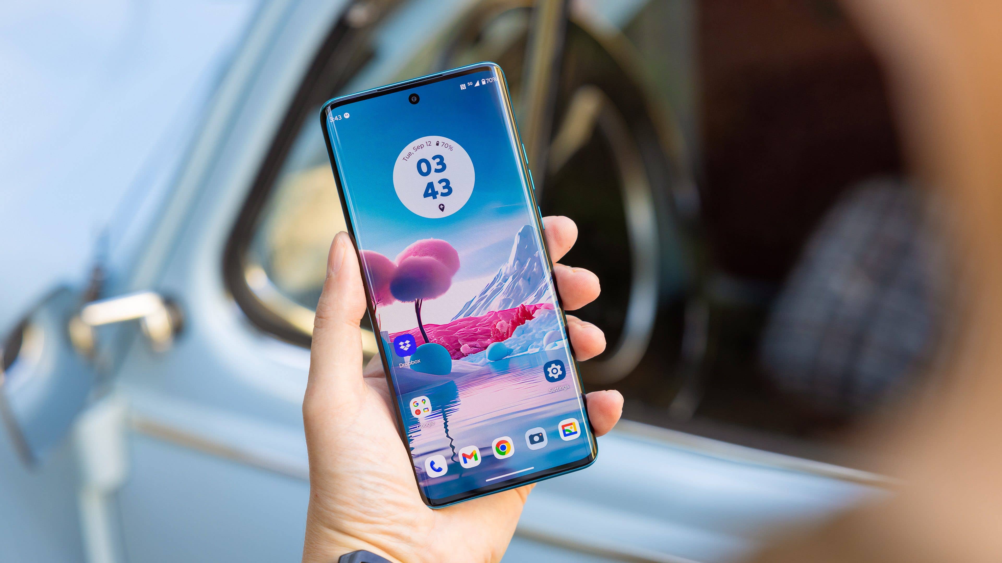 Le Motorola Edge 40 Neo tenu dans une main gauche et vu de face avec son écran allumé Le Motorola Edge 40 Neo tenu dans une main gauche et vu de face avec son écran allumé