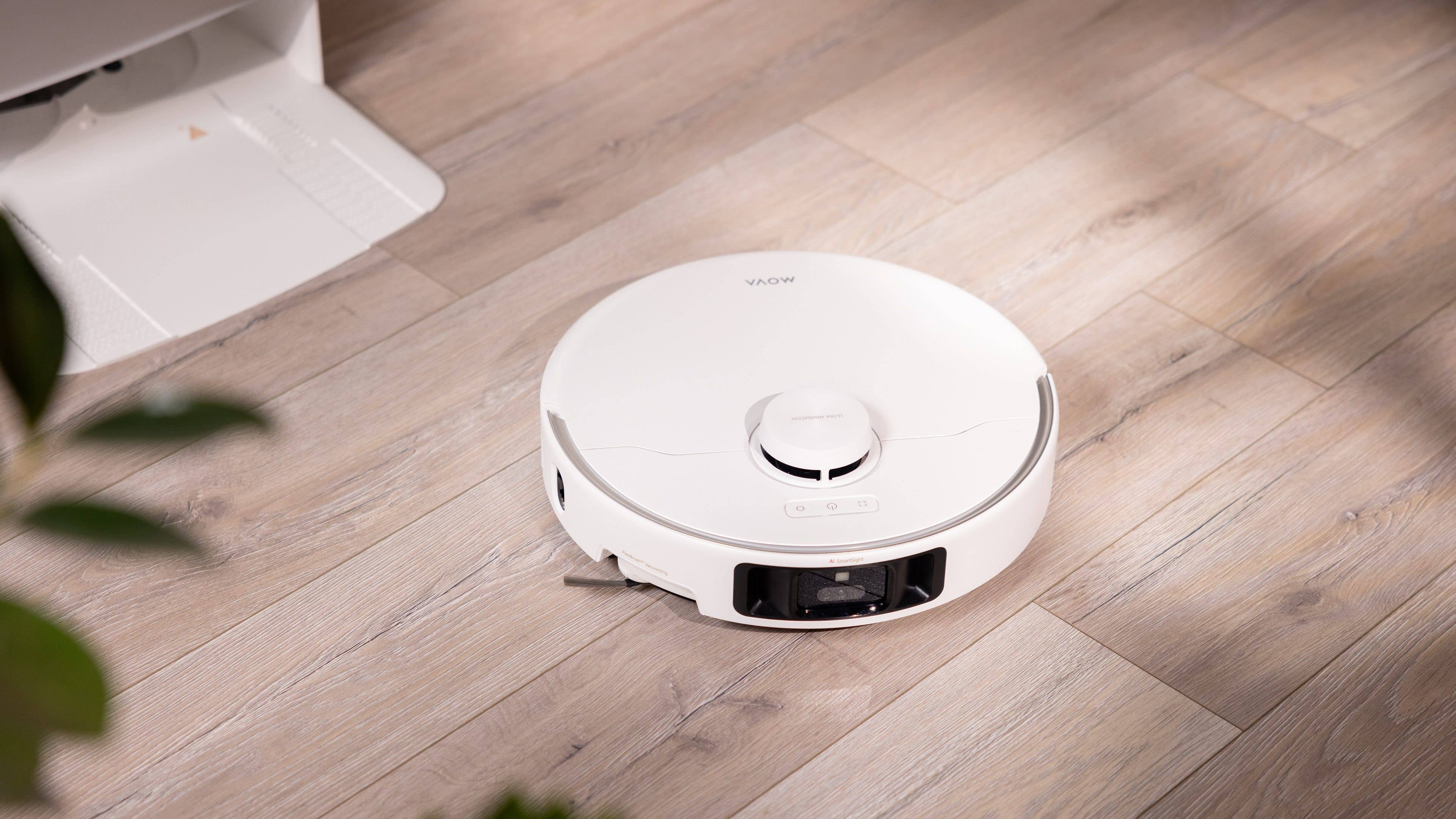 Un aspirateur robot blanc sur un sol en bois.