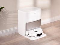 Un dock de robot aspirador Mova P50 Pro Ultra en un interior moderno con suelo de madera y una planta cercana.