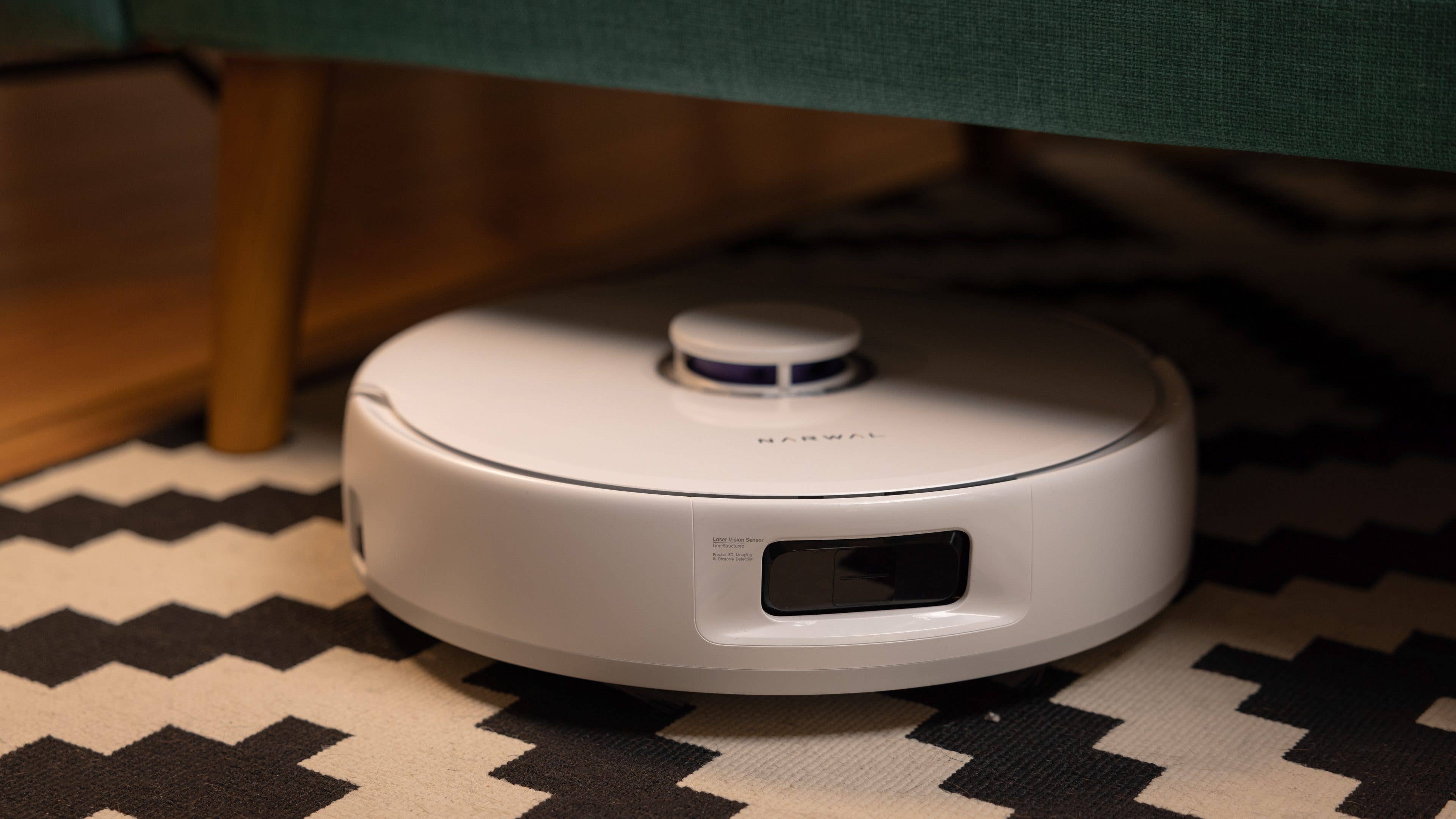 Le Narwal Freo X Ultra posé sur un tapis et caché sous un canapé