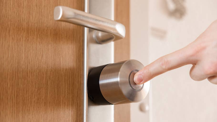 Une main appuie sur le bouton du0027un Nuki Smart Lock Pro monté sur une porte en bois.