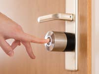 Une main s'apprête à toucher un Nuki Smart Lock Pro sur une porte.