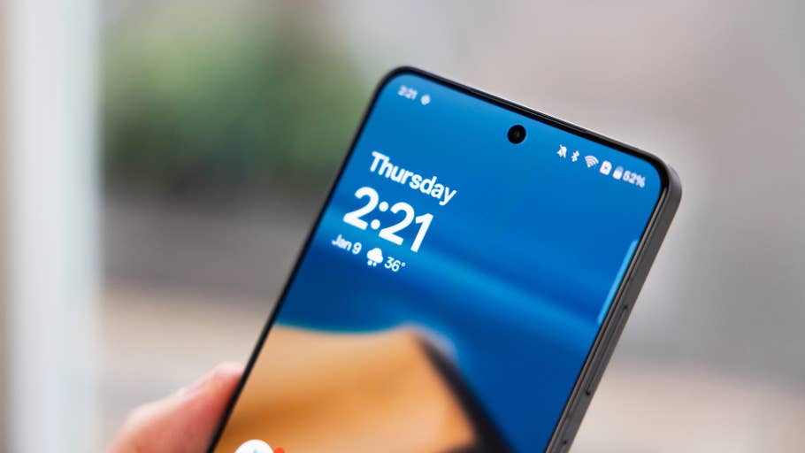 Gros plan du0027un smartphone affichant lu0027heure 2:21 et la date 9 janvier sur un fond bleu clair.