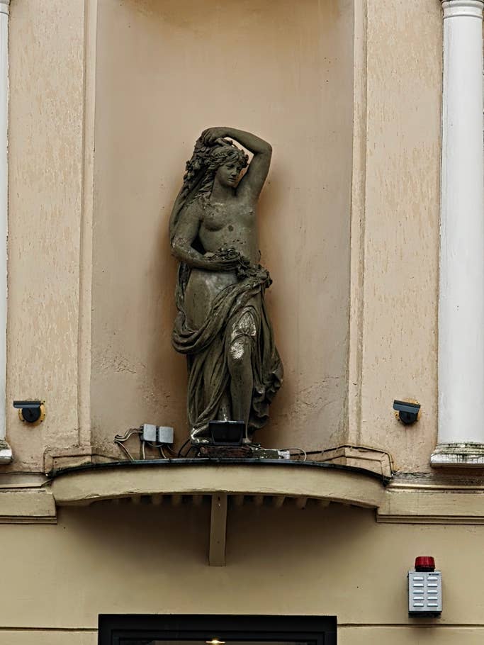 Une statue du0027une femme tenant des fleurs sur la façade du0027un bâtiment.