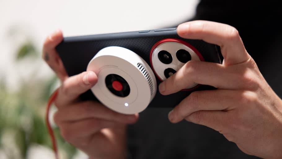 Une personne tenant un smartphone OnePlus 13 avec un accessoire photo.