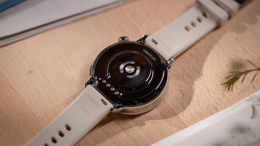 Aperçu du dos de la OnePlus Watch 3 (43 mm) avec un bracelet blanc sur une surface en bois.