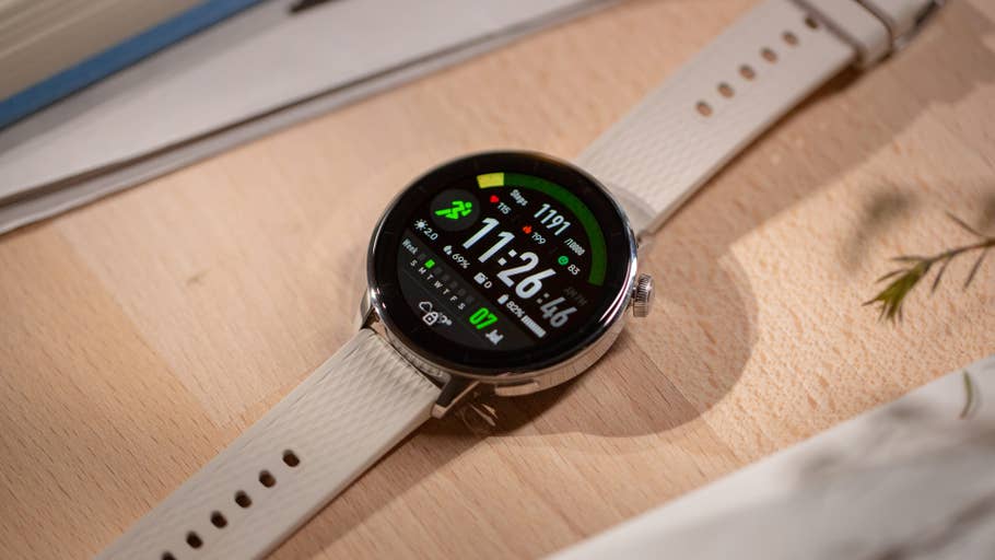 Une OnePlus Watch 3 avec un cadran rond affichant des statistiques de sport, placée sur du bois.