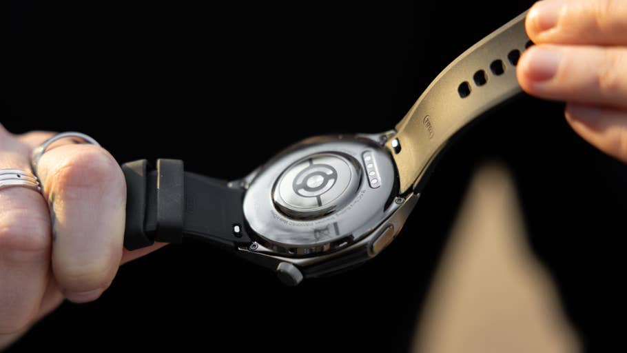 Une personne tient une montre OnePlus 3 noire, montrant les détails du dos et du bracelet.