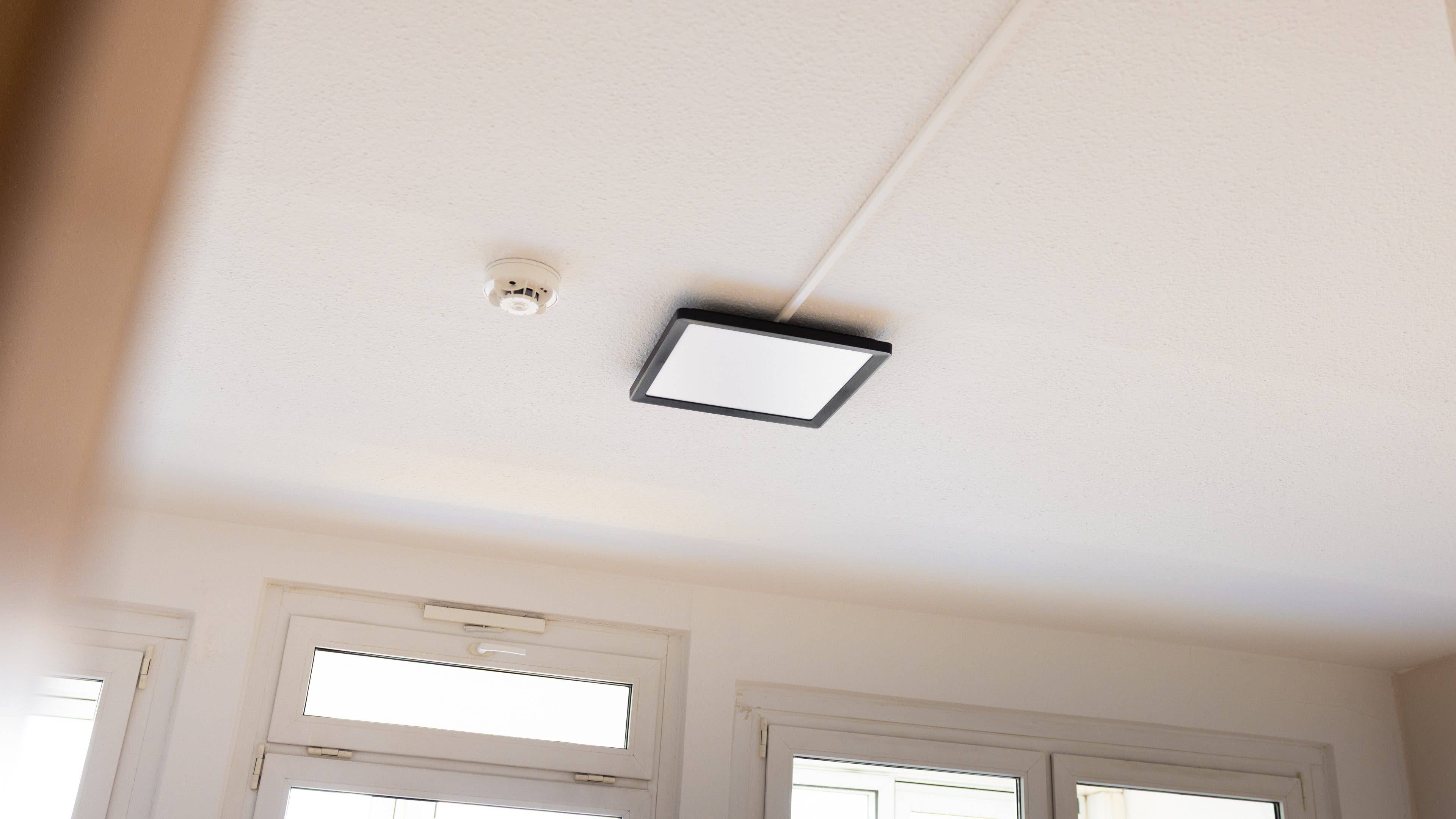 Un luminaire de plafond Philips Hue monté sur un plafond blanc dans une pièce lumineuse. Un luminaire de plafond Philips Hue monté sur un plafond blanc dans une pièce lumineuse.