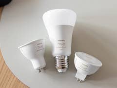 Trois ampoules intelligentes Philips Hue sur une surface claire.