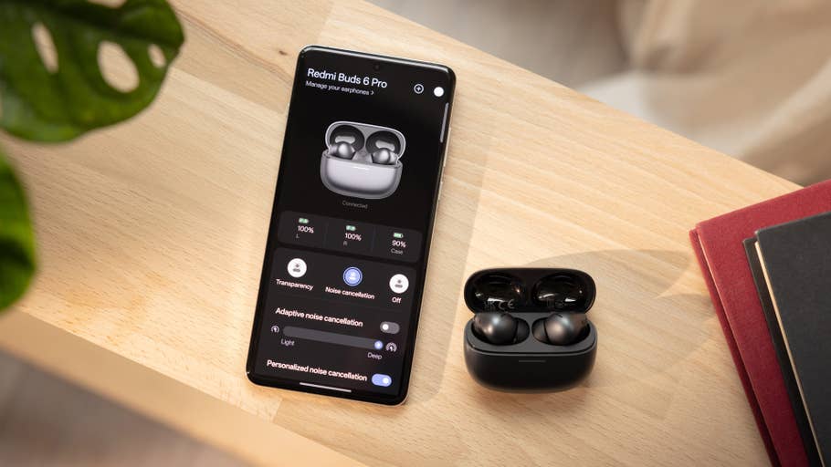 Redmi Buds 6 Pro affichés sur lu0027écran du0027un téléphone avec le boîtier des écouteurs sur une surface en bois.