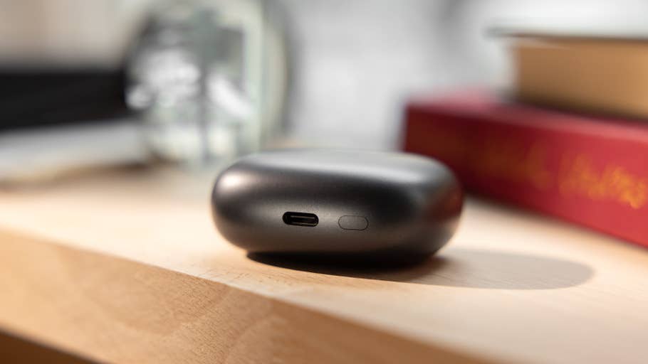 Gros plan du0027un boîtier de charge noir pour Redmi Buds 6 Pro sur une surface en bois.