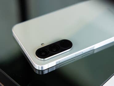 Un smartphone Samsung Galaxy A56 posé sur une surface en verre montre son module photo et son design.