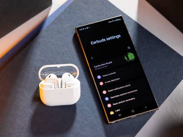 Boîtier de chargement Samsung Galaxy Buds 3 à côté d'un smartphone affichant les paramètres des écouteurs.