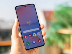 Une personne tenant un smartphone Samsung Galaxy S24 FE affichant une application météo avec une température de 34 °C.