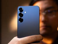 Une personne tenant un smartphone Samsung Galaxy S25 Plus avec un dos dégradé bleu et trois lentilles de caméra.