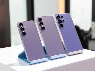 Trois smartphones Samsung Galaxy S25 exposés sur un support, mettant en avant leur design violet élégant.