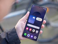 Une personne tenant un smartphone Samsung Galaxy S25 Ultra affichant des informations météorologiques et des icônes d'applications.