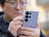 Un homme tenant un smartphone Samsung Galaxy S25 Ultra, utilisant son stylet, dans un environnement extérieur.