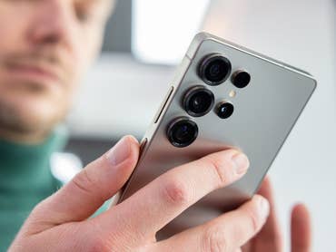 Une personne tenant un smartphone Samsung Galaxy S25, montrant les multiples objectifs de l'appareil photo.