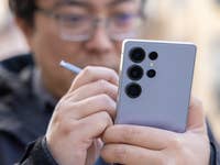 Une personne tenant un smartphone Samsung Galaxy S25 Ultra avec un stylet, se concentrant sur l'appareil photo.